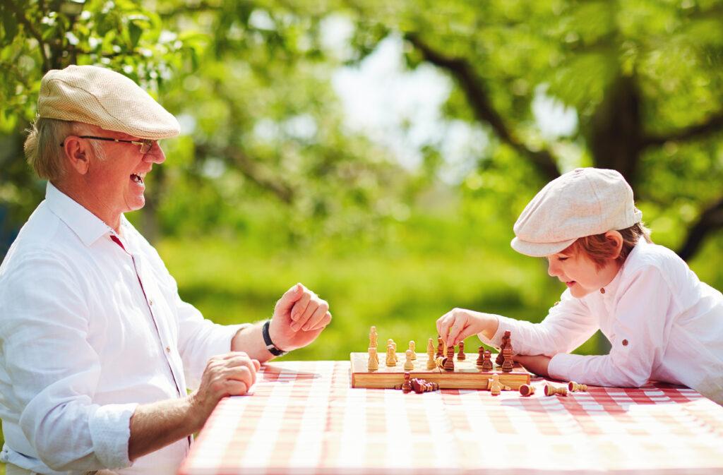 happy grandpa and grandson playing chess in spring garden